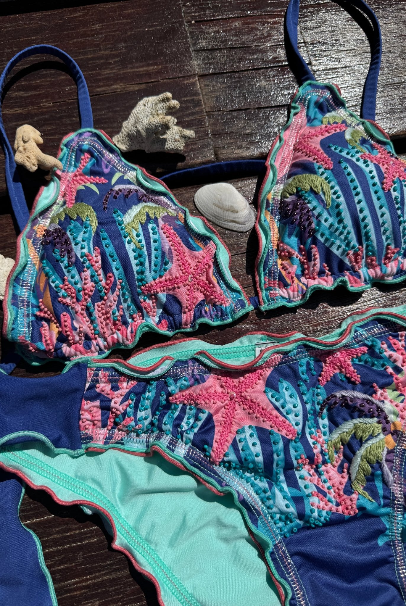CALASWIM Bahia hand beaded triangle bikini top on tropical wood with starfish and coral, luxury artisan swimwear